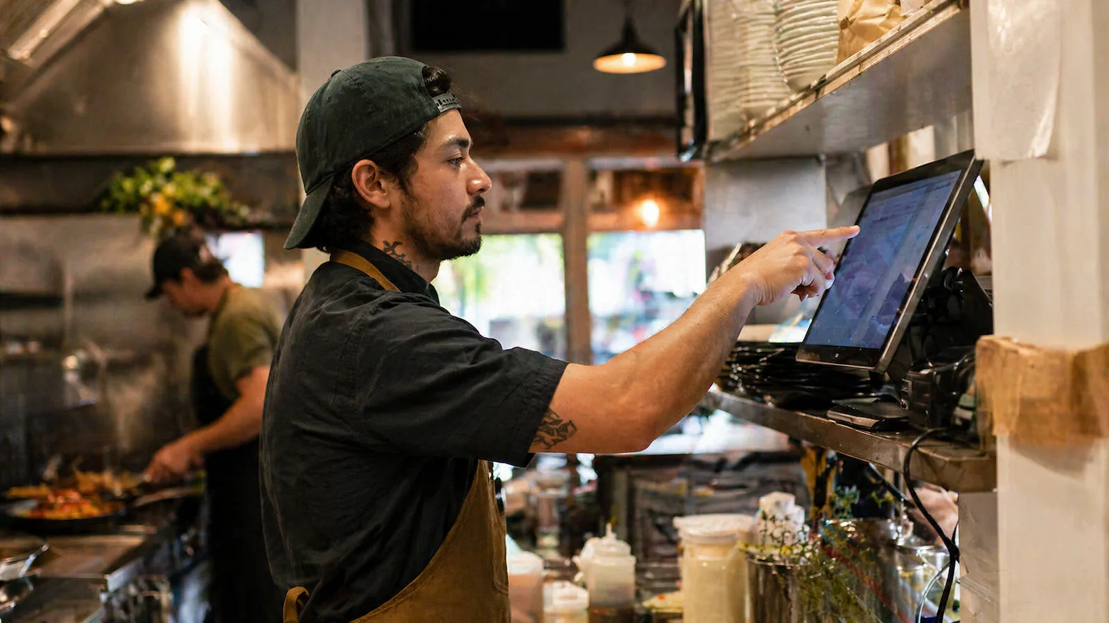 Chef using kitchen display system in busy restaurant kitchen during service